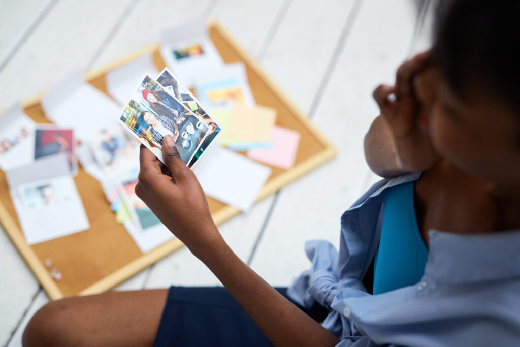 Woman looking through old photographs while reflecting on personal memories and past experiences.